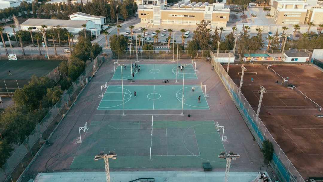 A red clay tennis court with a scenic Mediterranean landscape in the background