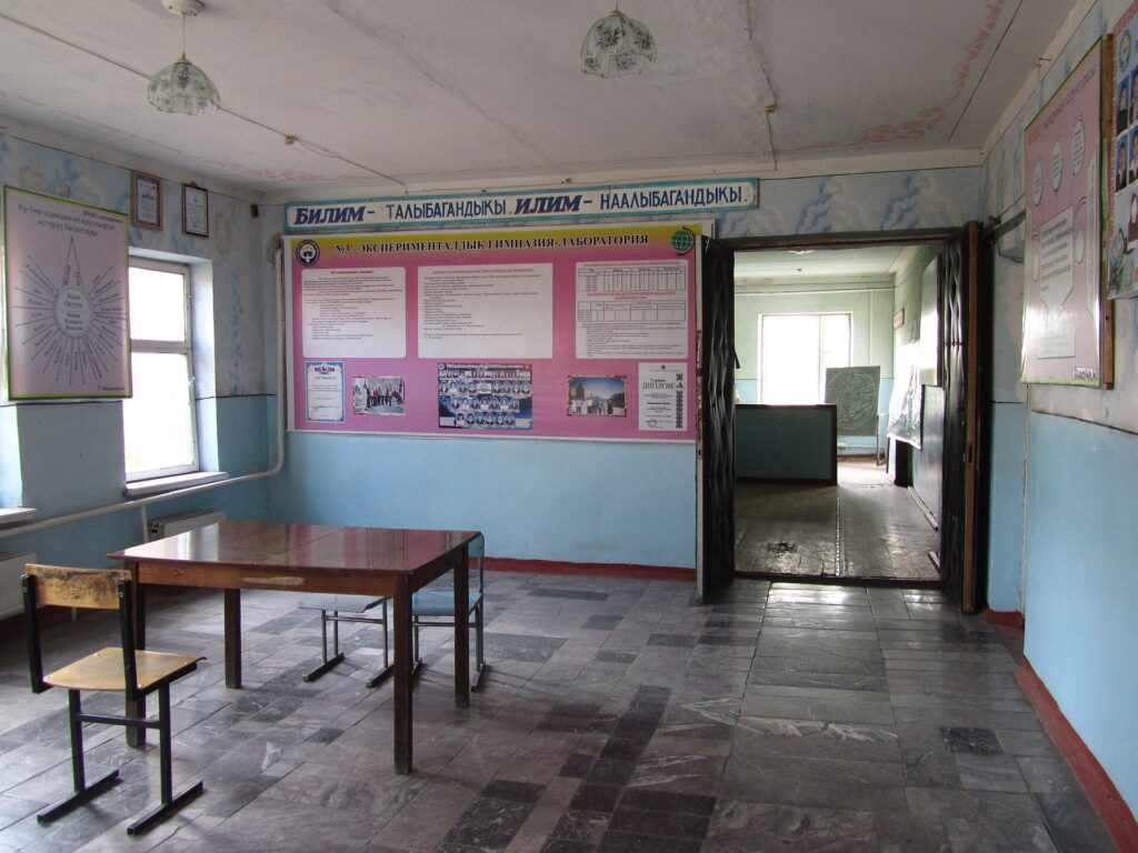 An empty school sports hall with markings on the floor and equipment stacked at one end