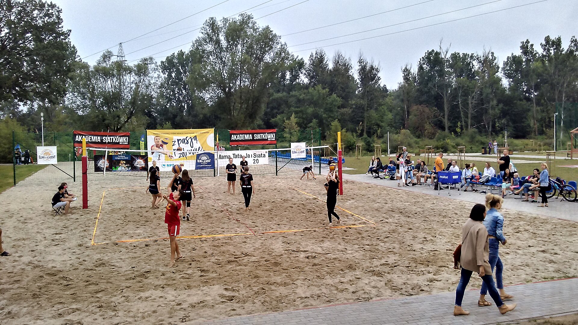 An indoor volleyball court with the net strung across the centre and empty seating behind