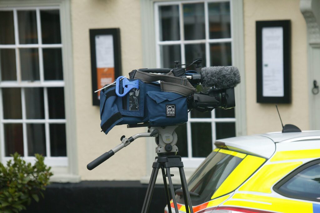A television camera mounted on a gantry above a stand pointing toward the playing area