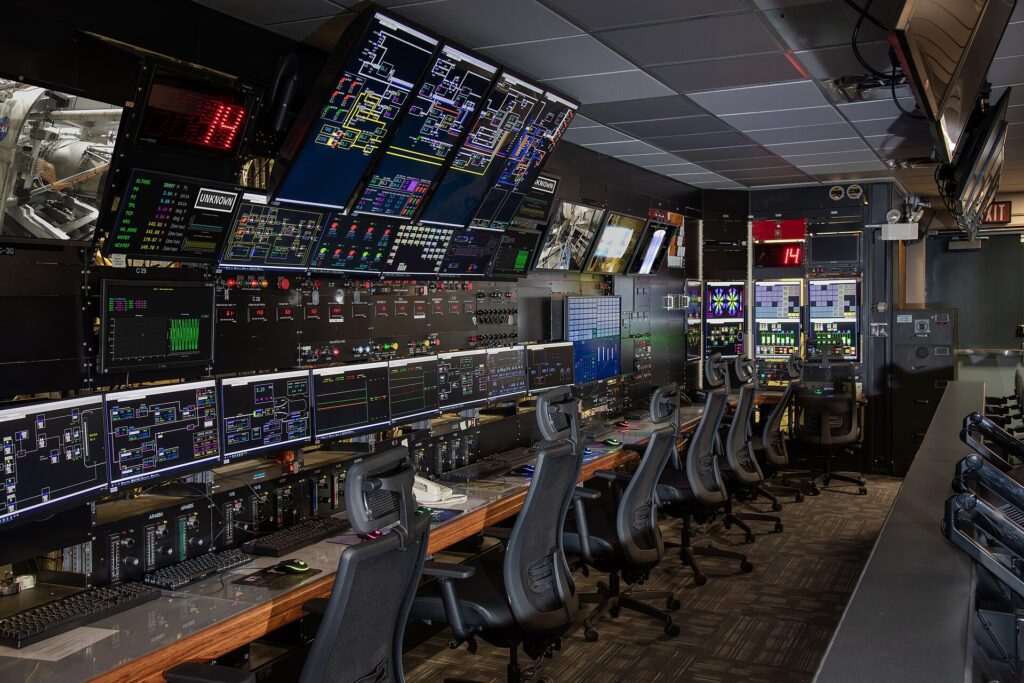 A bank of screens in a control room showing several camera angles of a pitch