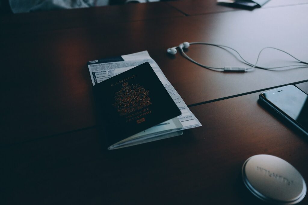 A passport and printed documents laid out on a desk beside a pen and a folder