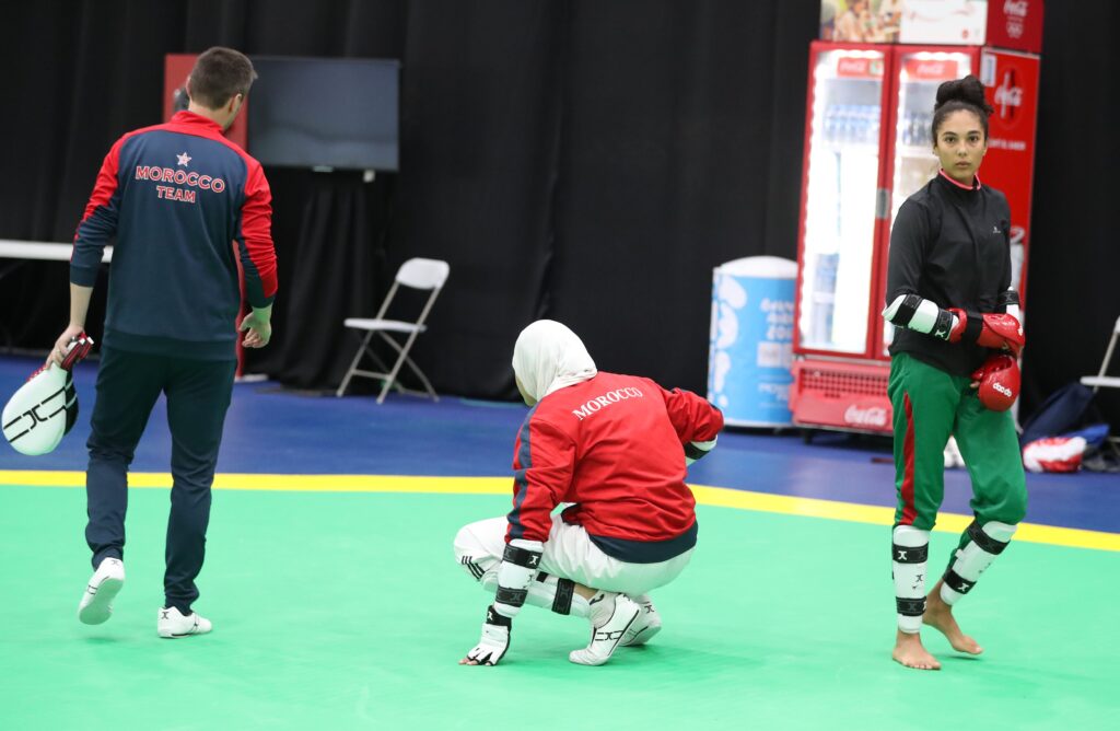 Students in a training hall practising kicks in rows on a matted floor