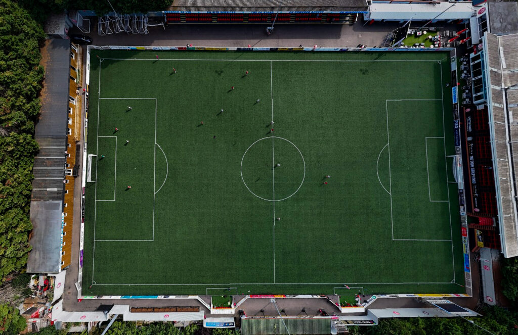 A football pitch seen from above showing the penalty areas and the centre circle