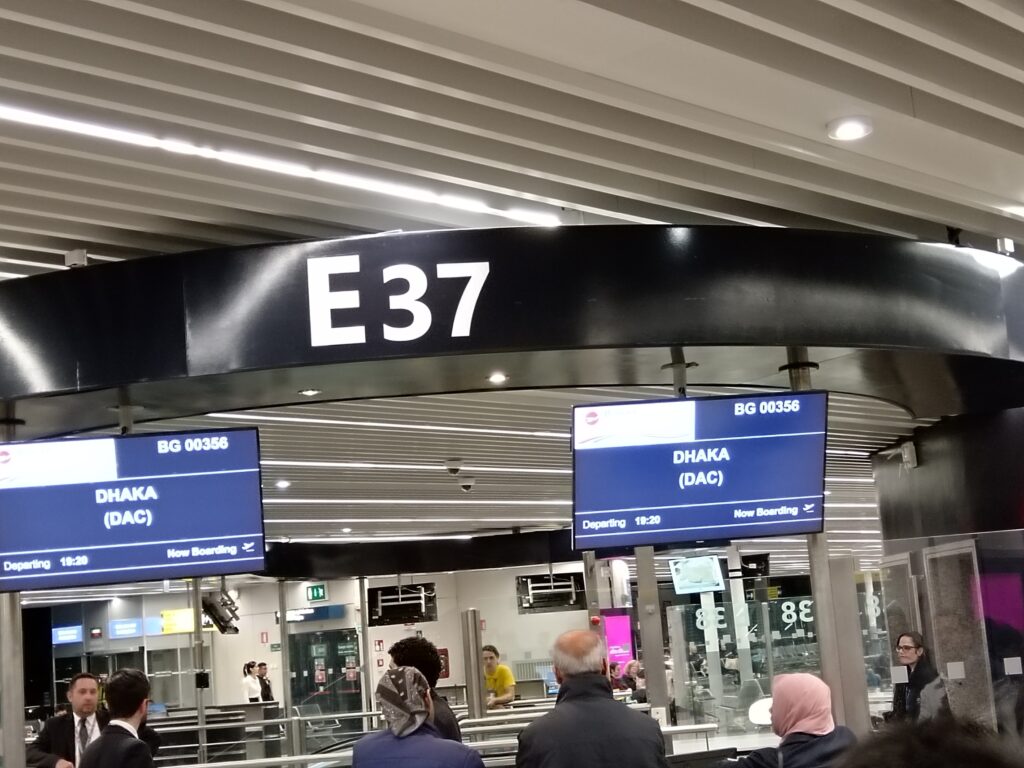 Travellers waiting beside a boarding gate inside an airport departure terminal