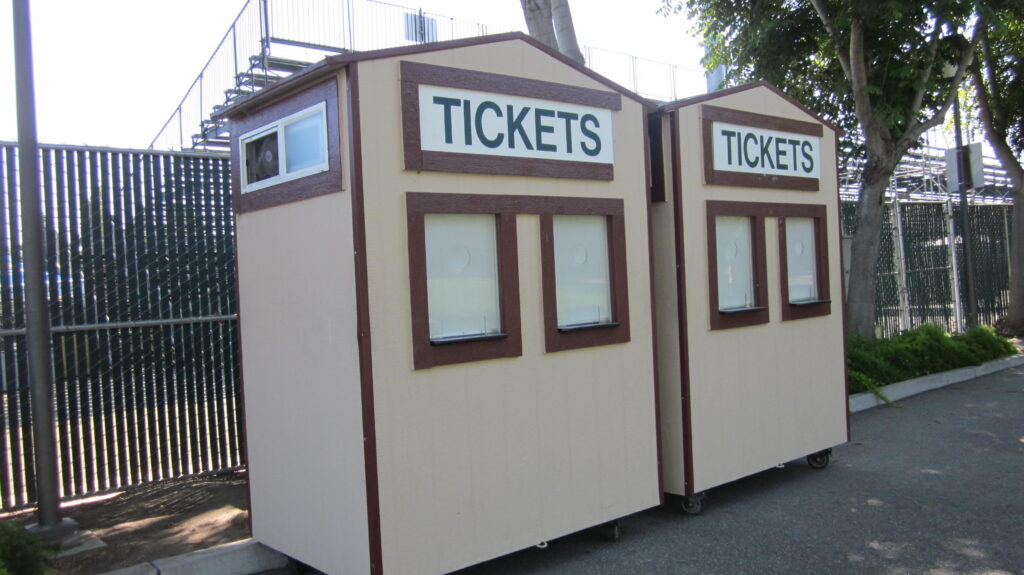 A closed ticket window at a sports ground with printed signage above the counter