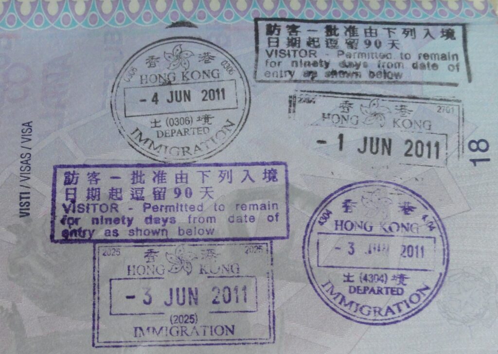 A passport open on a desk next to stamped travel documents and an identity card