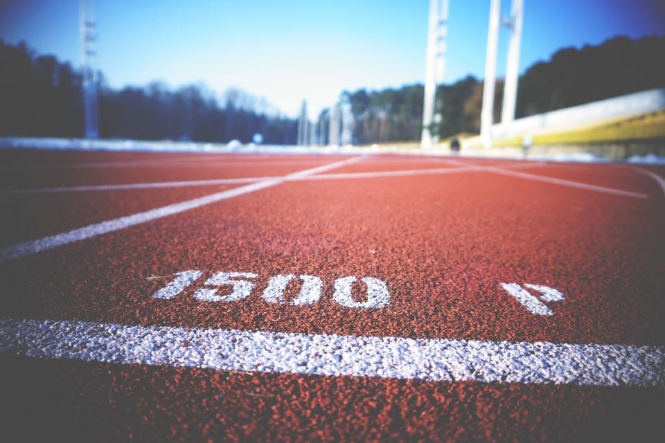 Empty red athletics track lanes marked with white lines seen from ground level