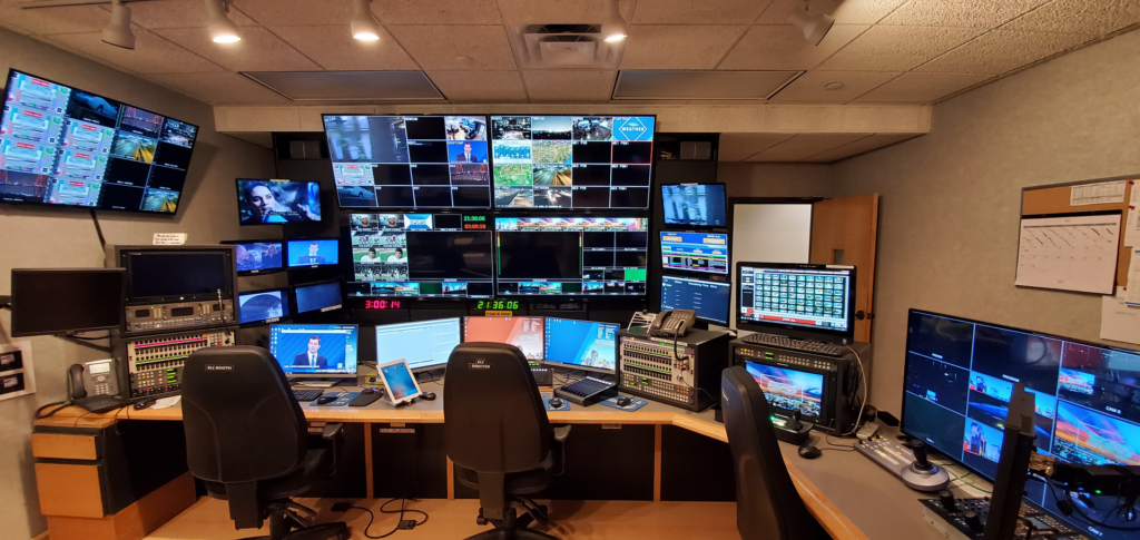 A gallery of monitors and mixing desks staffed during a live sports transmission