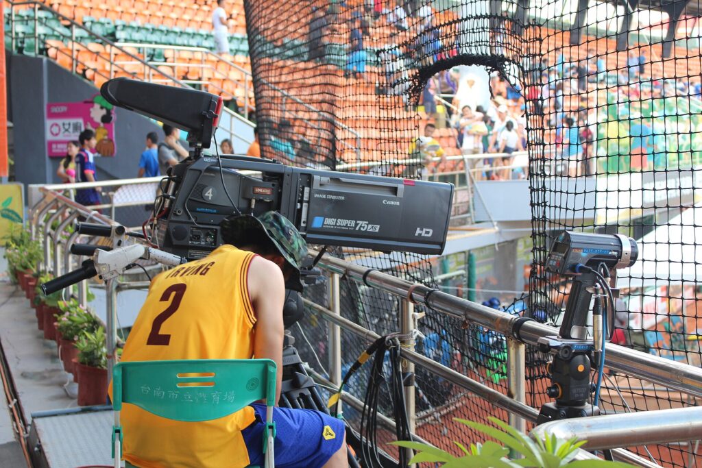 A raised filming platform with railings above the seating tier of a football ground