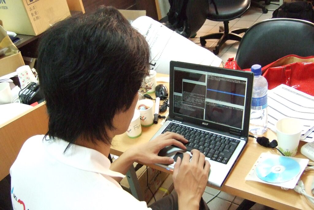A laptop on a table showing a football pitch while a phone rests alongside it