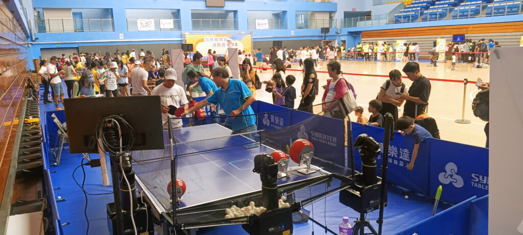 Rows of table tennis tables in a bright hall with young players rallying