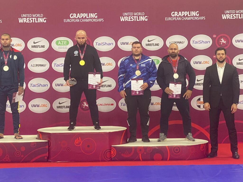 One wrestler working from the top position over an opponent on the competition mat