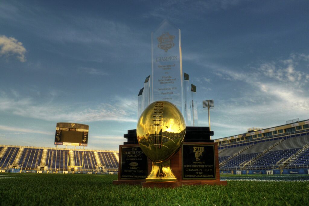 A silver football trophy standing on a plinth against a dark background