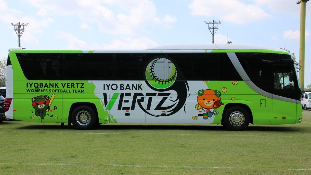 A team bus parked outside an airport terminal loading luggage before travel