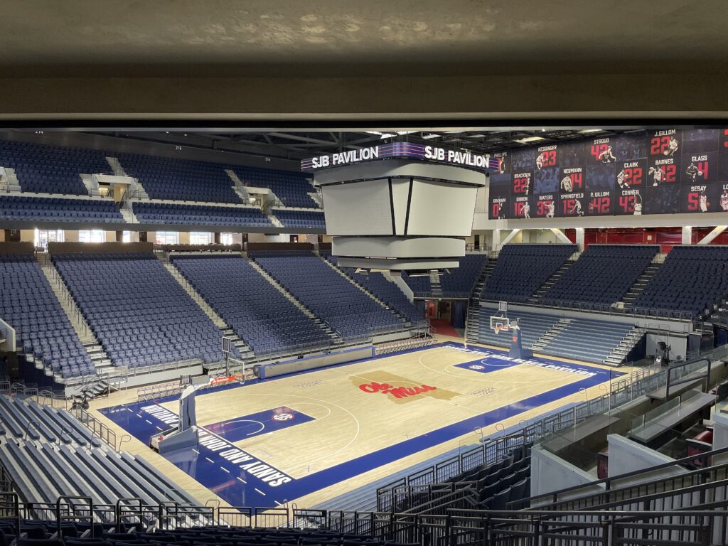 A basketball hoop and backboard seen from the baseline of an empty indoor court