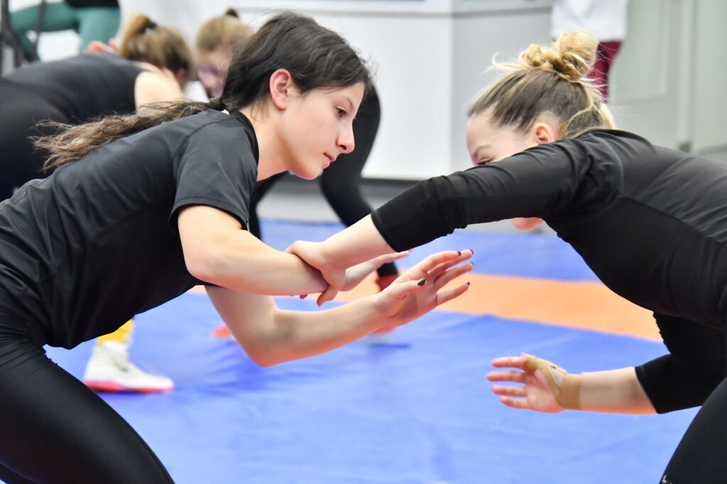 Wrestlers drilling takedowns in pairs during a training session on a large mat
