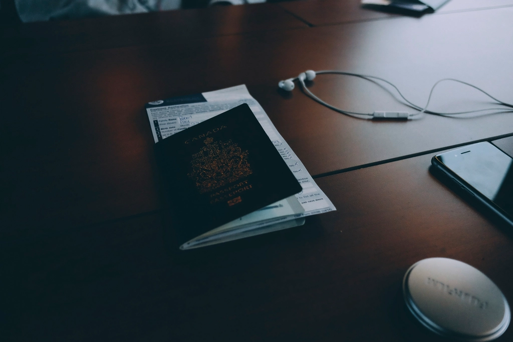 A passport and identity documents arranged on a desk beside a pen